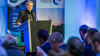 ZUG Geschäftsführerin Corinna Enders elegant schwarz gekleidet spricht an einem Rednerpult vor einem blau beleuchteten Publikum 