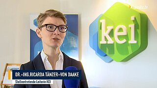 Die stellvertretende Leiterin des KEI Dr. Ricarda Tänzer-von Daake gibt ein Interview vor dem KEI Logo.