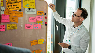 Ein TEilnehmer pinnt einen Zettel an eine Pinnwand während eines Workshops.