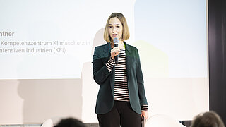 Constanze Haug hält Ansprache auf der Bühne vor einem großen Bildschirm