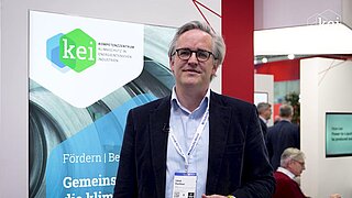 Abbildung einer PowerPoint Folie, ein Foto, auf dem ein Mann vor einem Rollup steht. 