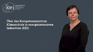 eine stehende Person, neben ihr an der Wand ist Text 