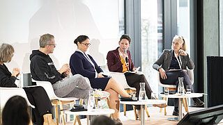 Die Teilnehmenden der Podiumsdiskussion Moderatorin Hanna Gernsmann, Dr. Christian Bogatu, Claudia Martina Buhl, Dr. Wibke Lölsberg sowie Nilgün Parker (von links nach rechts) sitzen auf Stühlen auf der Bühne und diskutieren.