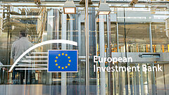 Schild mit dem Logo der Europäischen Investitionsbank an der modernen Glasfassade ihres Hauptsitzes.