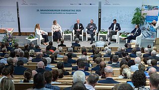Menschen diskutieren auf dem Podium vor Publikum