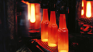 Drei glühende Glasflaschen in der Produktion 