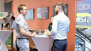 Drei Personen im Gespräch an einem Stehtisch