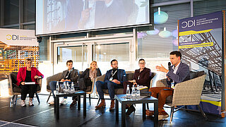 Eine Bühne, auf der sechs Personen sitzen und angeregt diskutieren.