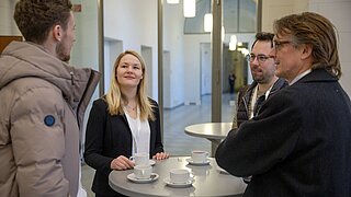 Vier Personen an einem Stehtisch diskutieren.